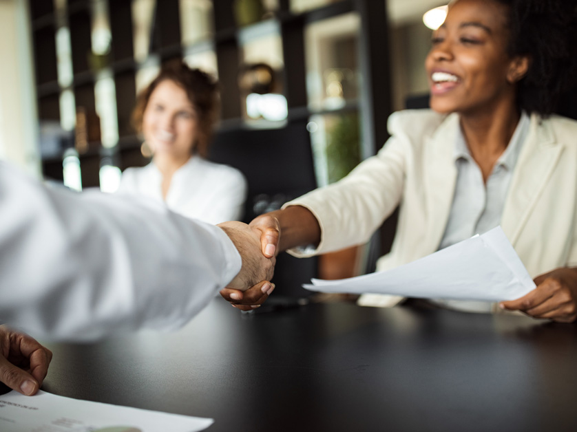 handshake between multiple people in board room
