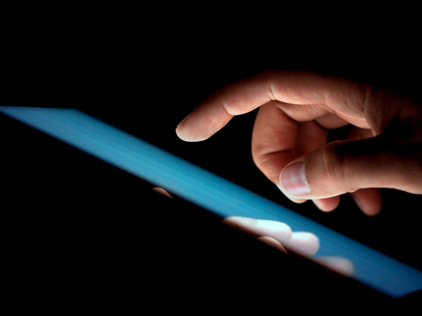 close up of fingers on tablet screen in the dark