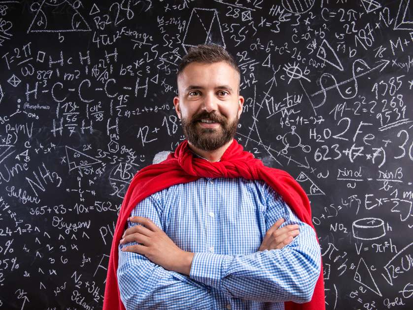 man wearing red cape in front of math chalkboard