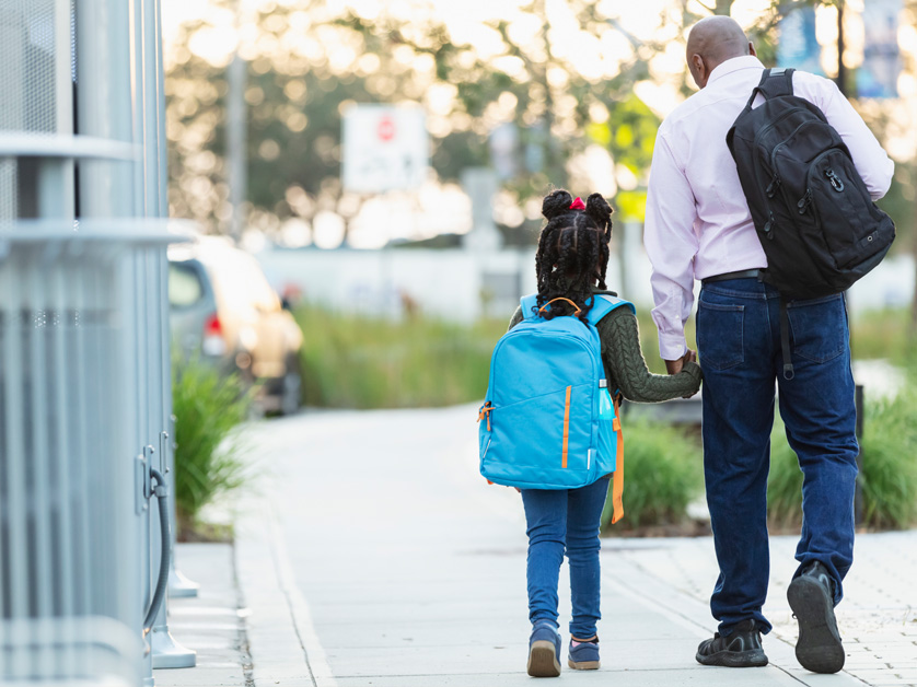 father and daughter with backpacks walking outside