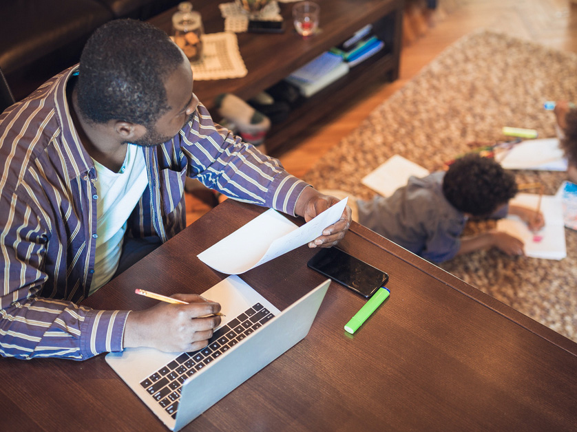 father working at a table with kid on floor