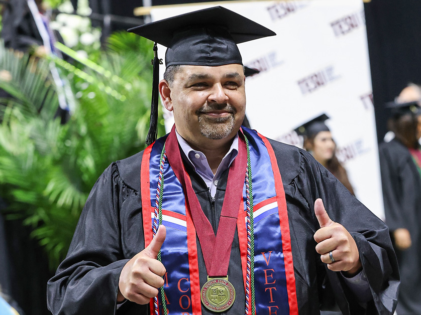 graduate giving thumbs up at commencement ceremony