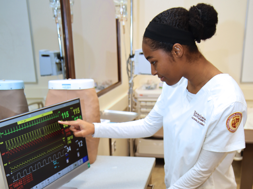 female nursing student at computer monitoring heart rates