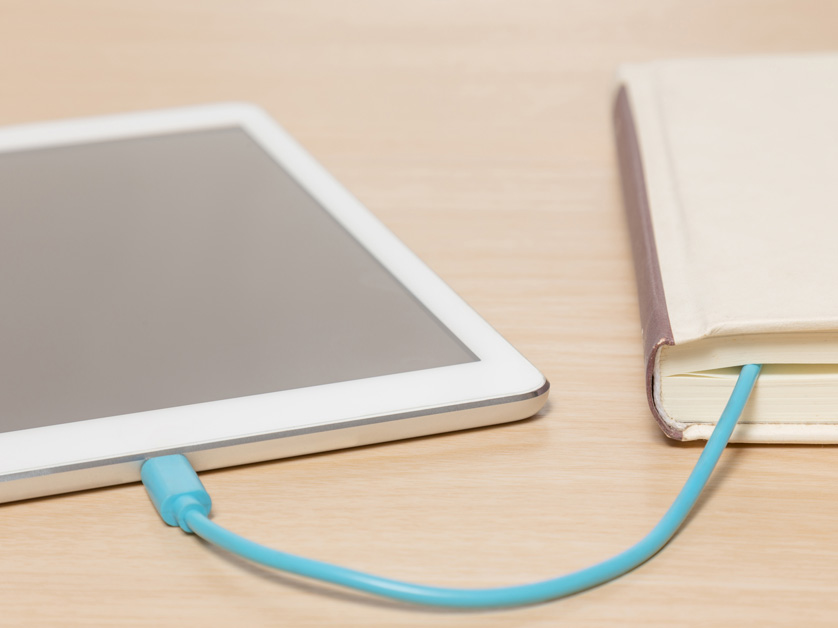 tablet plugged in with cord to a book