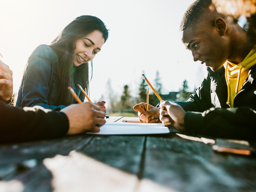 group of college students outside writing with pencils