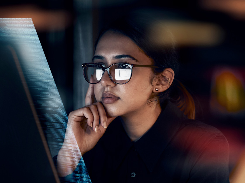 woman sitting in dark in front of computer code screen