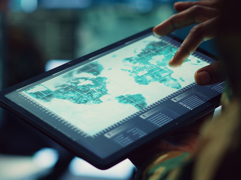 person holding tablet touching digital world map