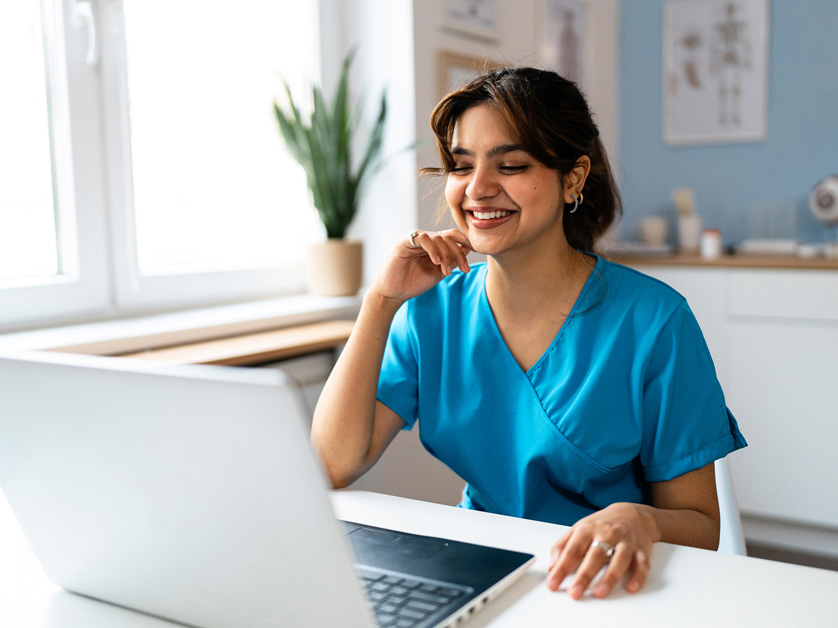 nurse sitting and smiling on laptop