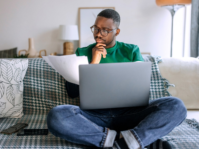 man curiously looking at laptop and papers