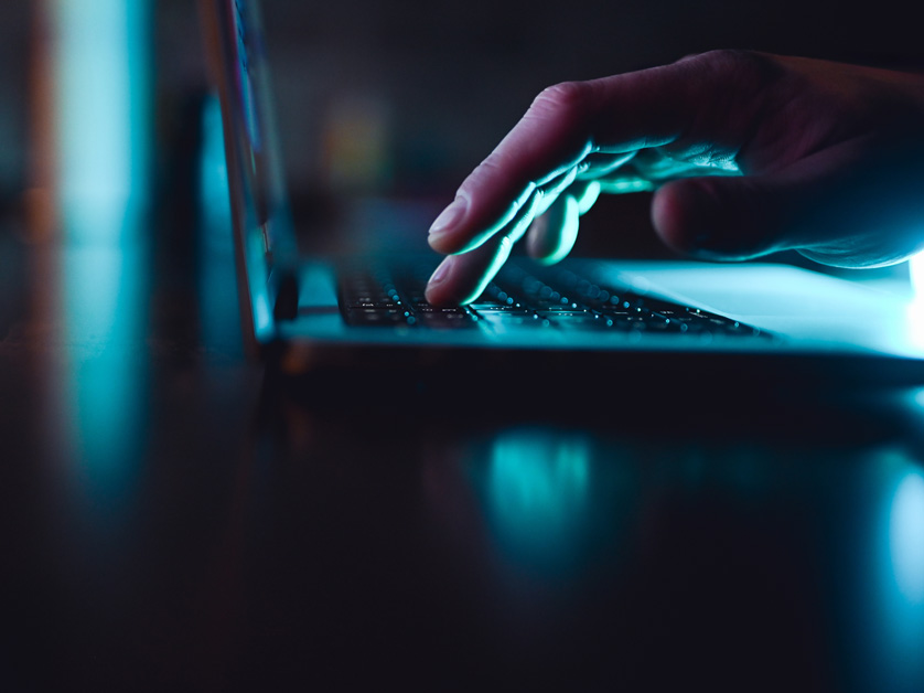 fingers at a laptop computer lit up in the dark