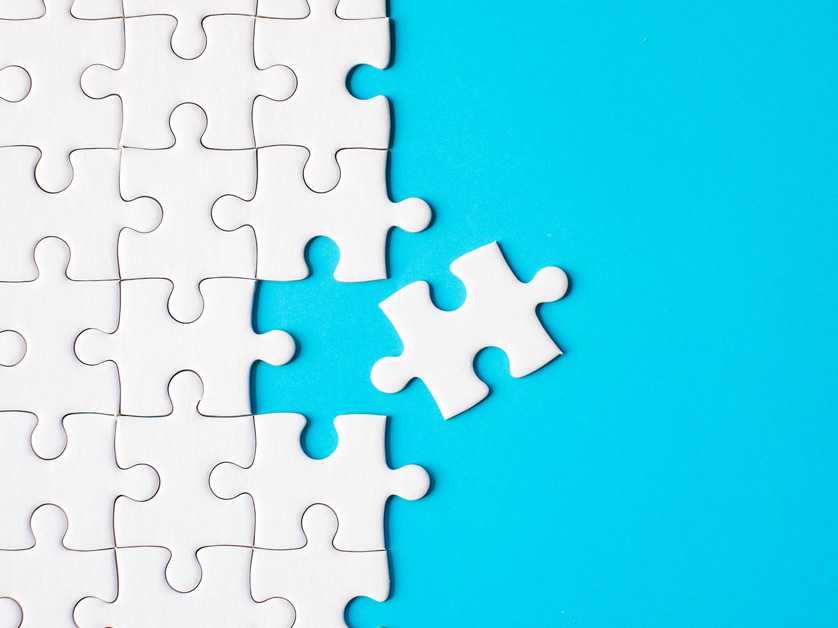 white puzzle piece fitting on blue background