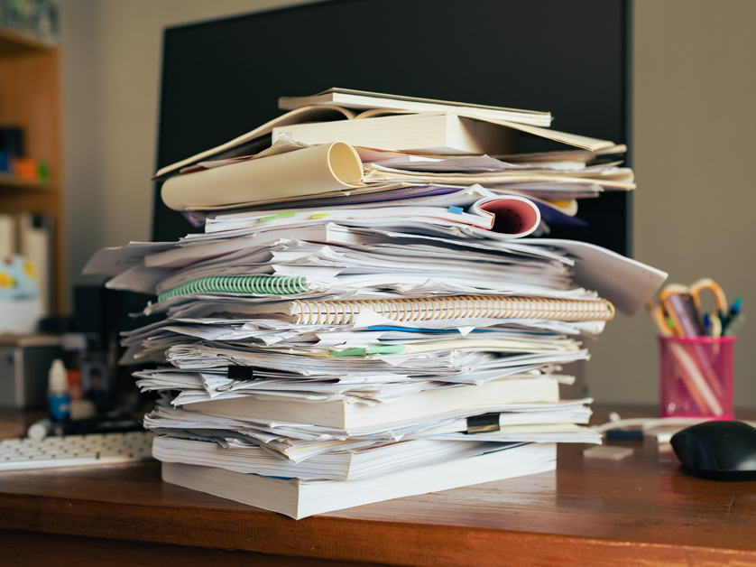 stack of messy papers and books on desk