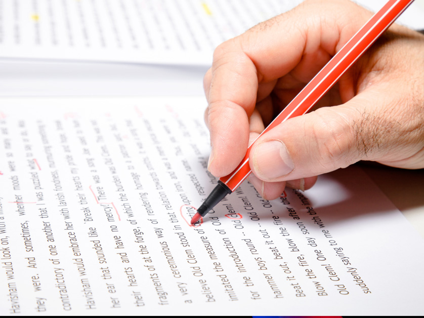 person proofreading editing paper in red ink