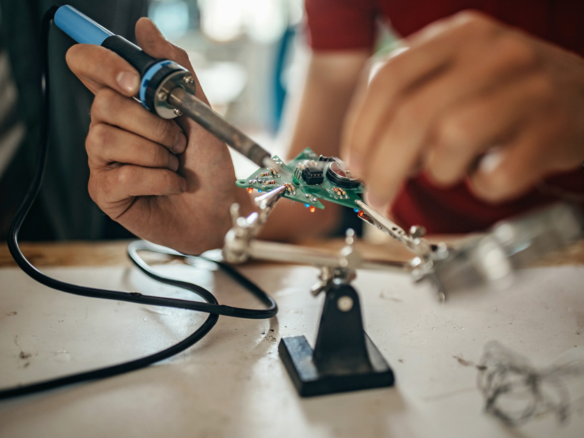 close up human hands soldering electrical circuits