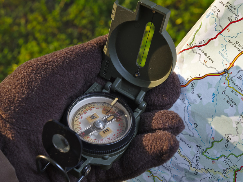 gloved hand holding compass and map outside