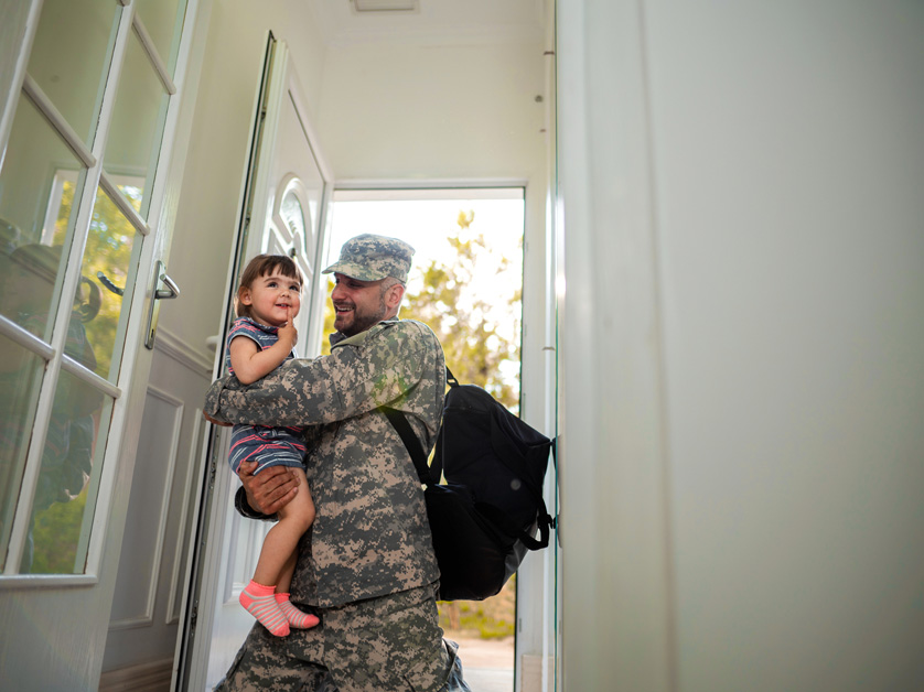 military father holds daughter in doorway