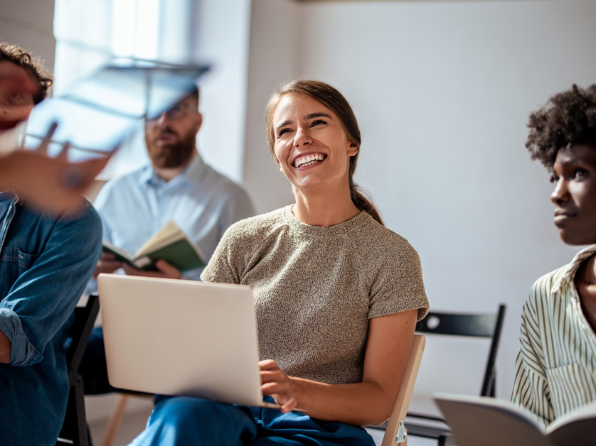 woman smiling with computer in circle of people