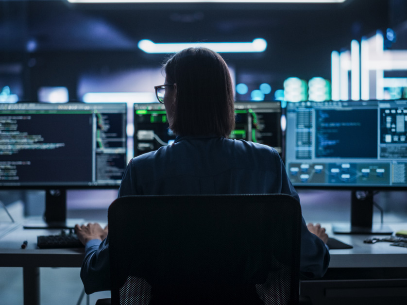 person sitting in front of multiple computer screens