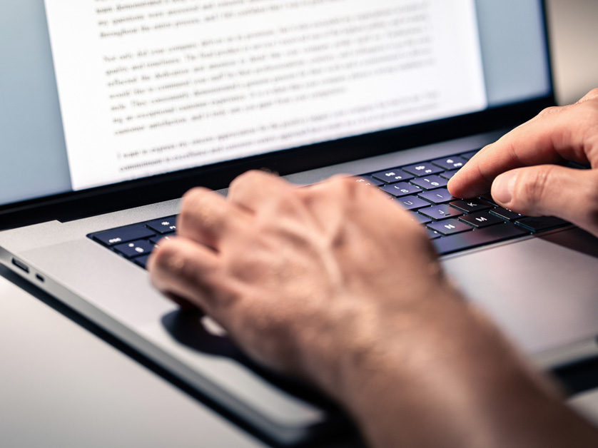 man typing an essay on laptop
