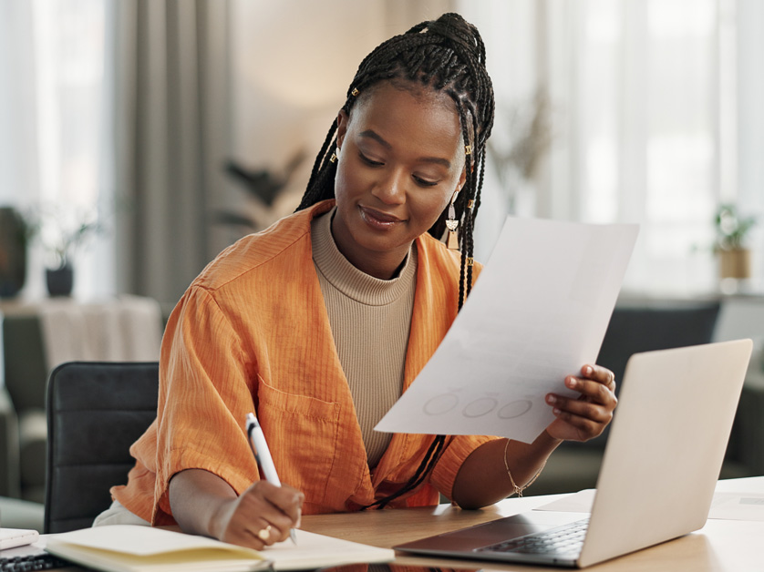 woman on laptop and writing in notebook
