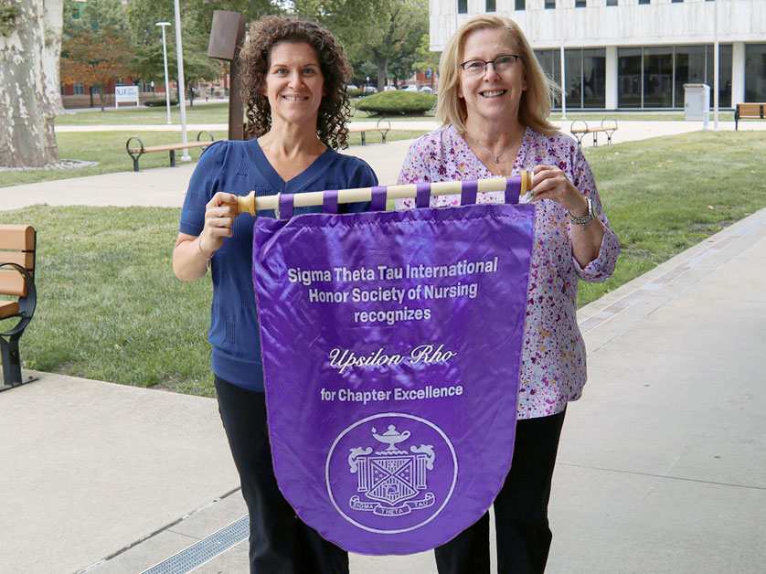 Holly Leahan and Maureen Clark-Gallagher holding Sigma Theta Tau International Honor Society of Nursing banner.