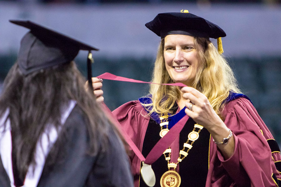 A woman prepares to place a medal around a student's neck.