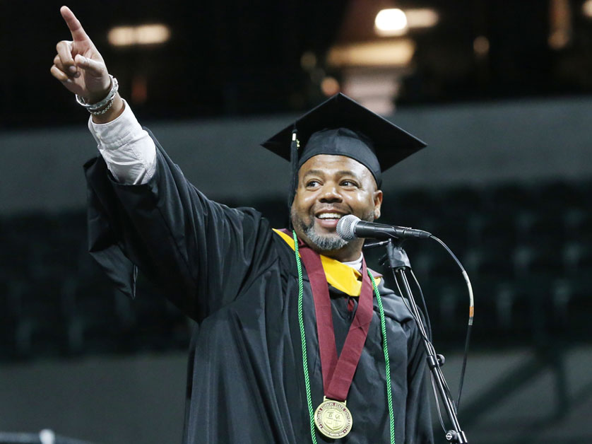 Thomas Edison State University student on stage in cap and gown addressing the attendees at a graduation ceremony